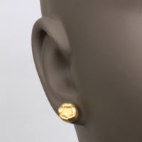 18k yellow gold stud earring on the earlobe of a woman with dark skin tone. These designer earrings are sold on ezzykaia’s online jewelry boutique with other contemporary fine jewelry designs that are made locally in New York City
