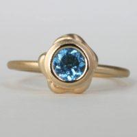 Front view of an14k yellow gold ring designed with a brilliant blue topaz gemstone.This luxurious gold single band ringcan be worn alone or as a double stackable ring. This fine jewelry collection is sold on ezzykaia’s jewelry online store with available free shipping.