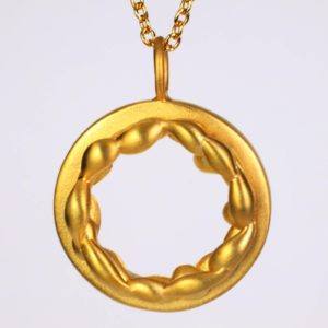 A close up showing the 18k yellow gold pendant necklace adorned with 18K yellow gold chain. This round gold pendant is presented with a cascading metal texture on top of a solid gold pendant base. This fine jewelry collection is made with love inNew York City