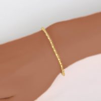 an 18K yellow gold bracelet on a women’s wrist. This new genuine gold bracelet can be worn as a single or stackable bracelet. Ezzykaia’sfine jewelry collection is designed and made by a locally in Manhattan, New York