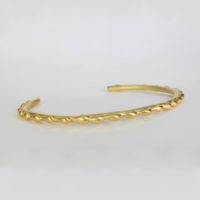 a 14k yellow gold petite size bracelet shown with a series of cascading genuine gold detail craftsmanship. This stackableslip on gold cuff can be made to order is 14k or 18k yellow gold by a local NYC fine jewelry designer