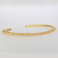 a18k yellow gold bracelet shown with a series of genuine gold detail design on top. This designer slip on gold cuff was created for full figure women and can be worn as a single or stackable bracelet. This fine jewelry is sold on Ezzykaia.com