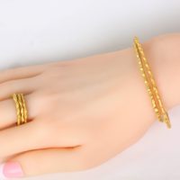 an 18k yellow gold stackable cuff with matching stackable rings on a woman’s hand. These fine jewelry are sold separately on Ezzykaia.com by a local New York jewelry artist and manufactured in the USA